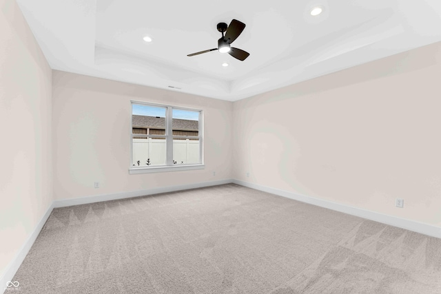 empty room featuring ceiling fan, a tray ceiling, and carpet flooring