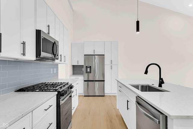 kitchen featuring white cabinetry, appliances with stainless steel finishes, light stone countertops, pendant lighting, and sink