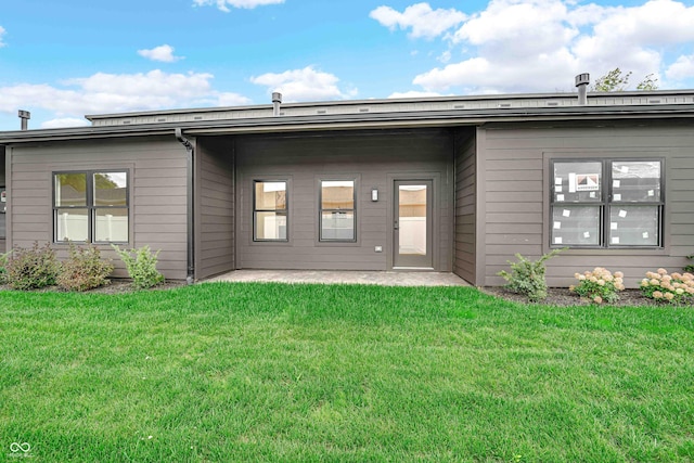 rear view of property featuring a patio area and a lawn