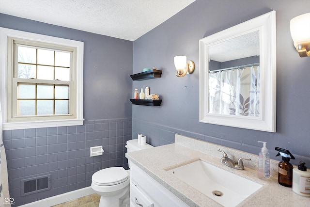 2934 S Irwin St, Indianapolis, IN 46203 - full bathroom featuring vanity, a textured ceiling, toilet, tile walls, and a wainscoted wall