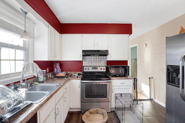 2934 S Irwin St, Indianapolis, IN 46203 - kitchen featuring stainless steel appliances, under cabinet range hood, dark wood-style floors, white cabinetry, and decorative light fixtures