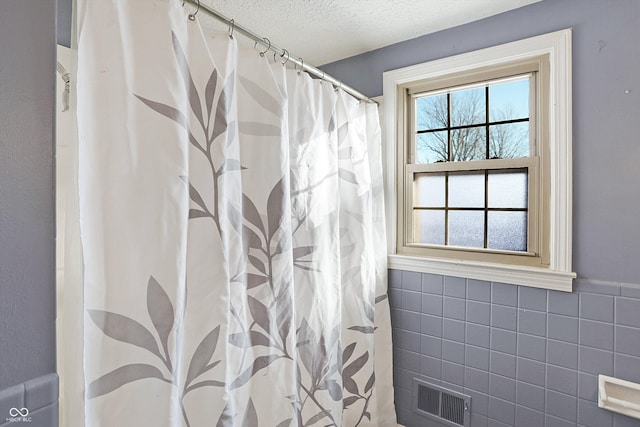 2934 S Irwin St, Indianapolis, IN 46203 - full bath with tile walls, a textured ceiling, a shower with curtain, and wainscoting