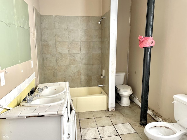 full bathroom featuring tiled shower / bath, vanity, and toilet