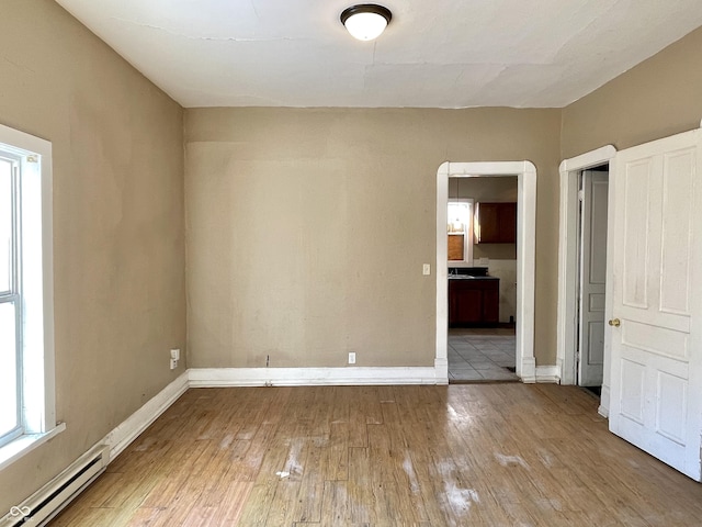 spare room with a baseboard radiator and light hardwood / wood-style floors