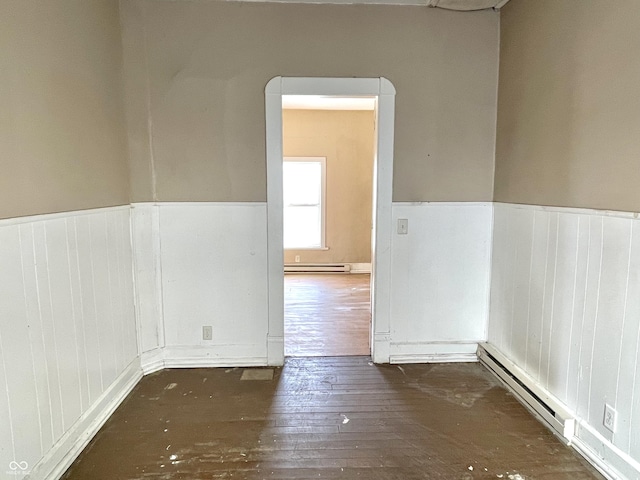 spare room featuring dark wood-type flooring and a baseboard radiator