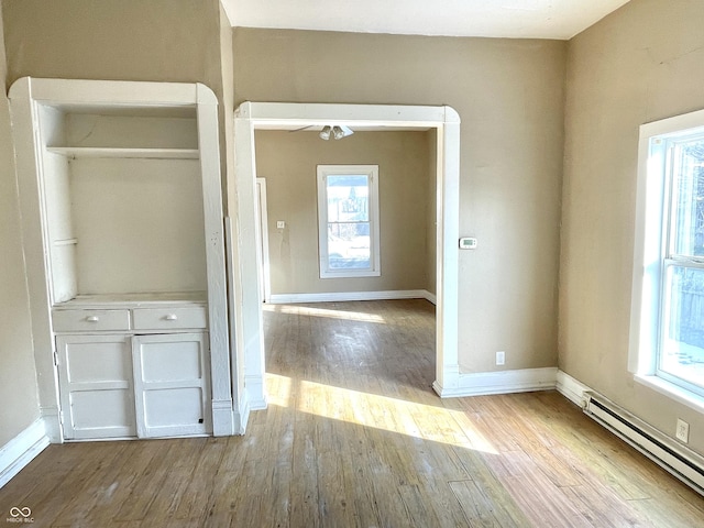 interior space with a baseboard radiator, a healthy amount of sunlight, and light hardwood / wood-style flooring