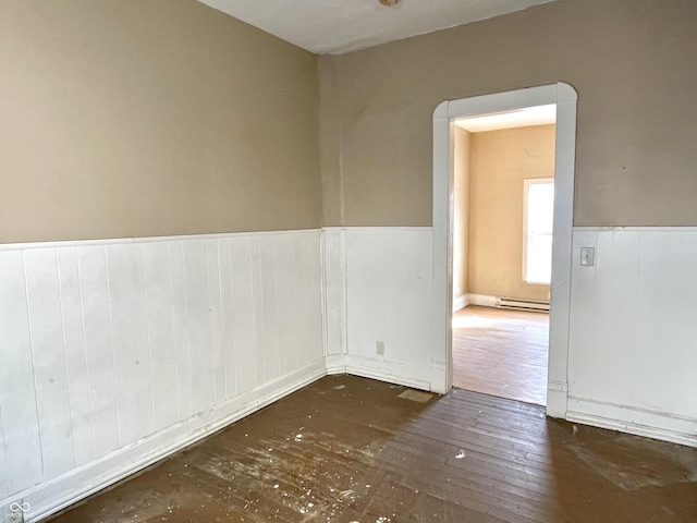 spare room featuring a baseboard radiator and dark hardwood / wood-style floors