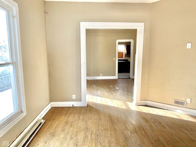 unfurnished room featuring a wealth of natural light, light hardwood / wood-style floors, and baseboard heating