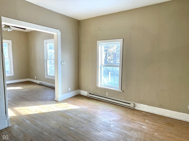 spare room with baseboard heating, ceiling fan, and light hardwood / wood-style flooring