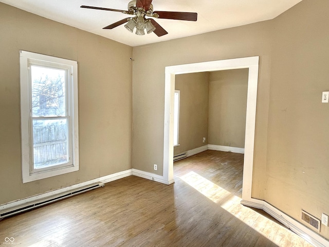 spare room with ceiling fan, hardwood / wood-style floors, and a baseboard heating unit