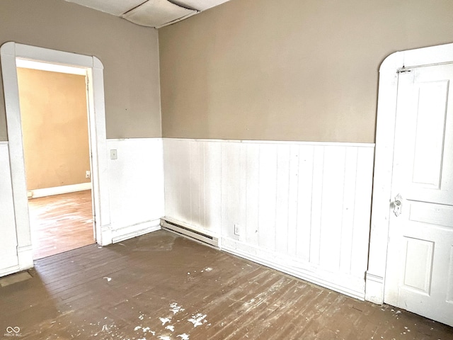 spare room with dark wood-type flooring and a baseboard radiator