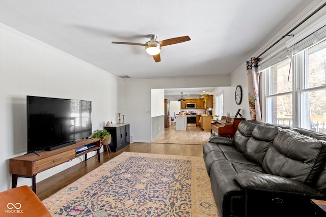 living room with ceiling fan, light wood-type flooring, and ornamental molding