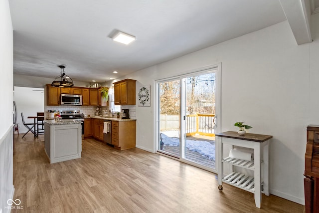 kitchen with tasteful backsplash, pendant lighting, light hardwood / wood-style flooring, light stone countertops, and stainless steel appliances