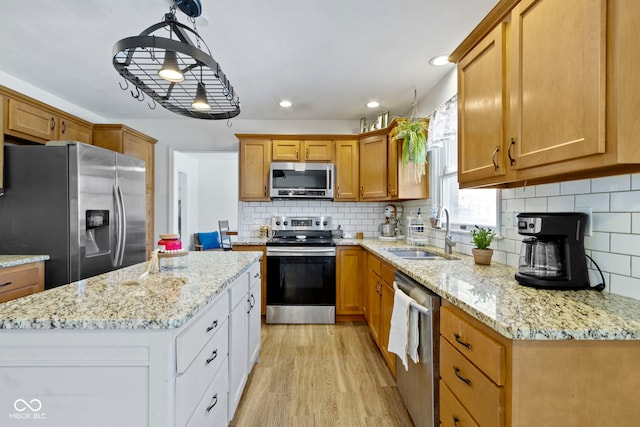 kitchen with appliances with stainless steel finishes, decorative backsplash, hanging light fixtures, white cabinets, and sink