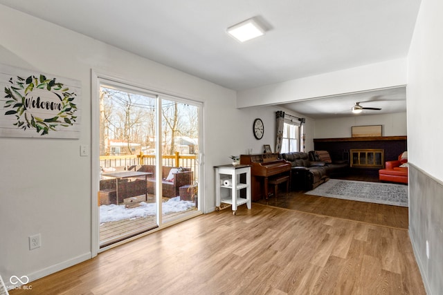 interior space featuring a brick fireplace, hardwood / wood-style flooring, and ceiling fan