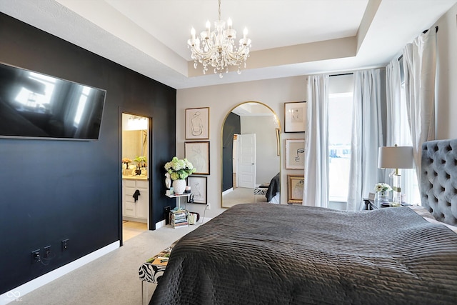 carpeted bedroom featuring connected bathroom, a notable chandelier, and a tray ceiling