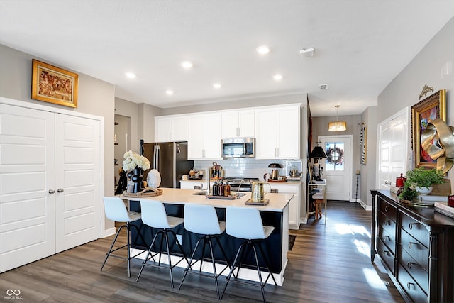 kitchen featuring stainless steel appliances, a breakfast bar area, a center island with sink, and white cabinets