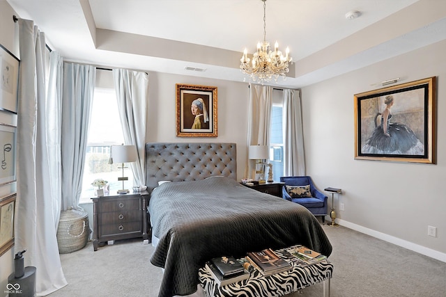 carpeted bedroom featuring an inviting chandelier and a tray ceiling