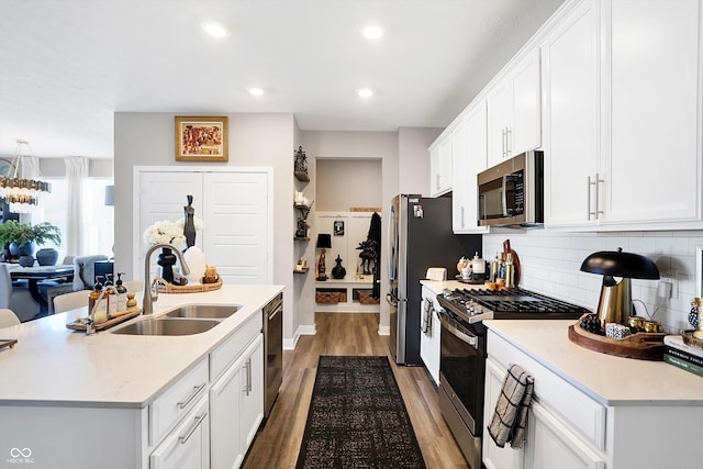 kitchen with sink, white cabinets, hardwood / wood-style flooring, stainless steel appliances, and a center island with sink