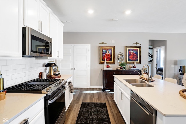 kitchen featuring sink, appliances with stainless steel finishes, white cabinetry, dark hardwood / wood-style floors, and a center island with sink