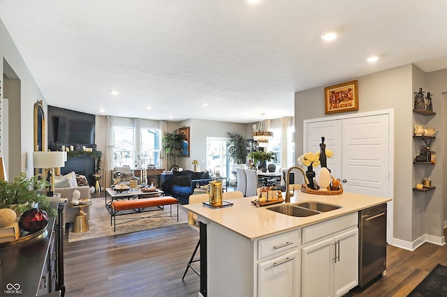 kitchen with a kitchen bar, sink, stainless steel dishwasher, a kitchen island with sink, and white cabinets