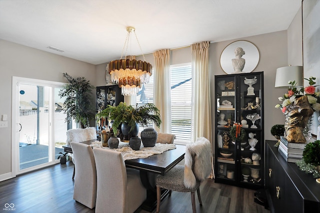 dining space featuring an inviting chandelier, plenty of natural light, and dark hardwood / wood-style floors