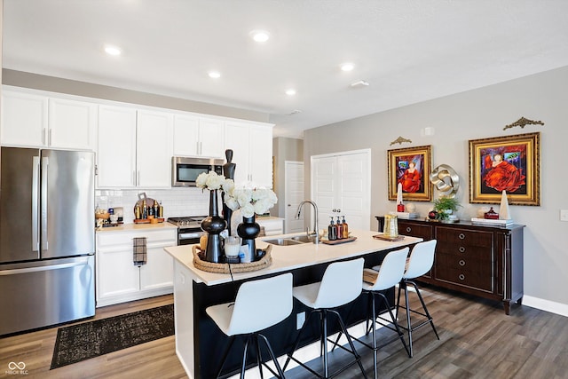 kitchen featuring stainless steel appliances, a kitchen island with sink, sink, and white cabinets