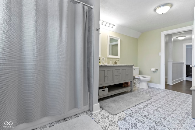 bathroom with toilet, vanity, lofted ceiling, and walk in shower