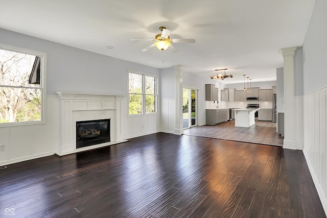386 White Oak Ln, Greenwood, IN 46142 - unfurnished living room featuring wainscoting, ceiling fan with notable chandelier, and dark wood-style floors