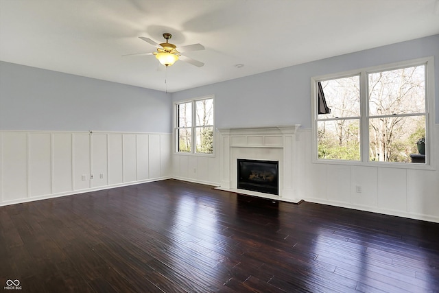 386 White Oak Ln, Greenwood, IN 46142 - unfurnished living room featuring wainscoting, ceiling fan, hardwood / wood-style floors, and a glass covered fireplace