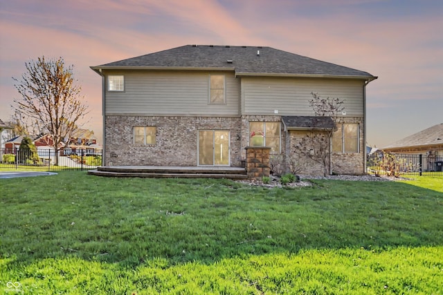 386 White Oak Ln, Greenwood, IN 46142 - back of property at dusk with a yard, fence, and brick siding
