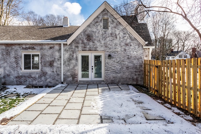 snow covered house featuring french doors