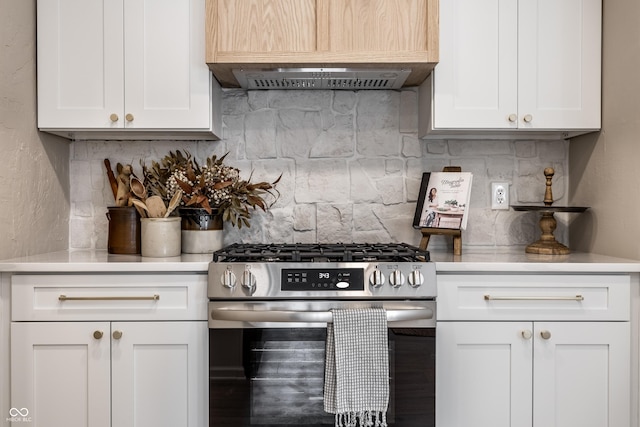 kitchen with stainless steel gas range oven, tasteful backsplash, and white cabinetry