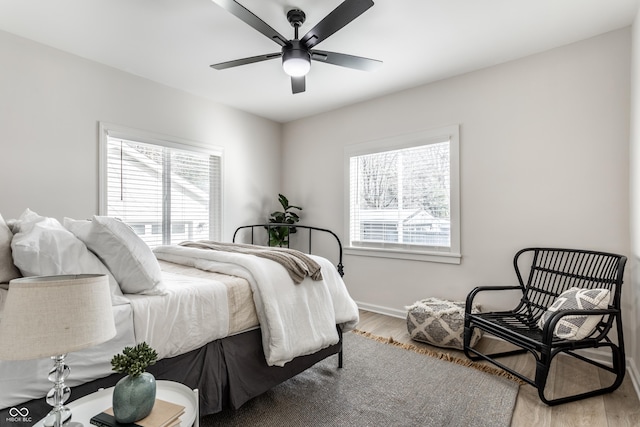 bedroom featuring hardwood / wood-style floors, multiple windows, and ceiling fan