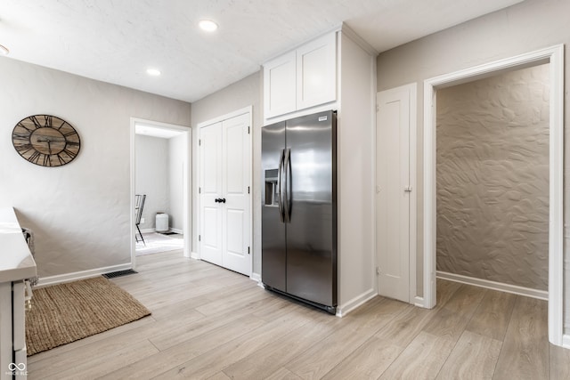 kitchen with stainless steel refrigerator with ice dispenser, white cabinets, and light hardwood / wood-style flooring