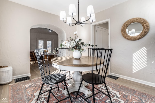 dining area with a chandelier, french doors, and hardwood / wood-style floors