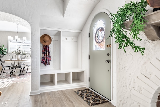 mudroom featuring hardwood / wood-style flooring, built in shelves, and an inviting chandelier