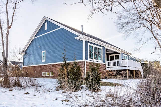 view of snow covered exterior with brick siding