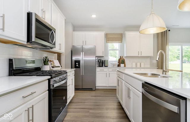 kitchen with sink, white cabinetry, pendant lighting, and stainless steel appliances