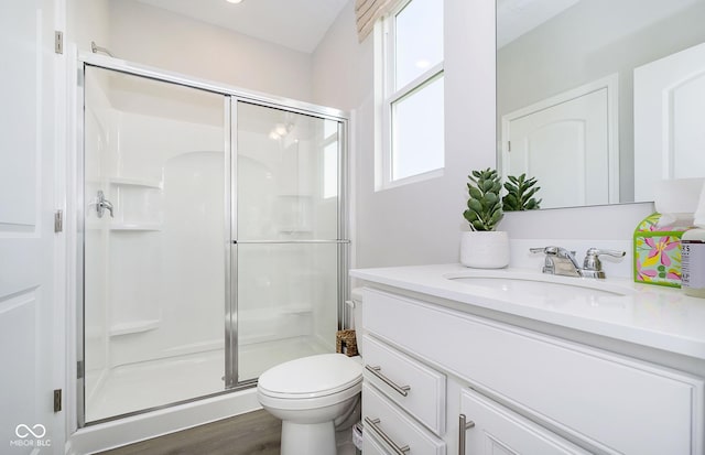 bathroom with wood-type flooring, toilet, a shower with door, and vanity