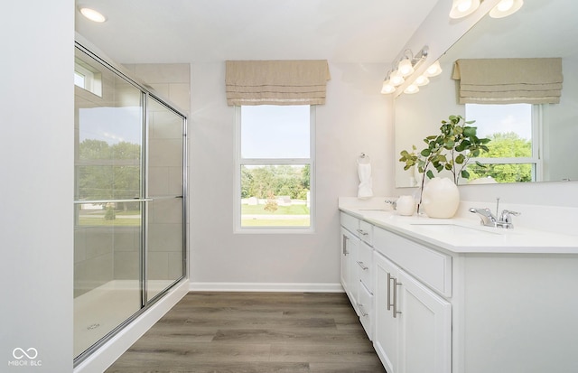 bathroom with hardwood / wood-style floors, a healthy amount of sunlight, walk in shower, and vanity