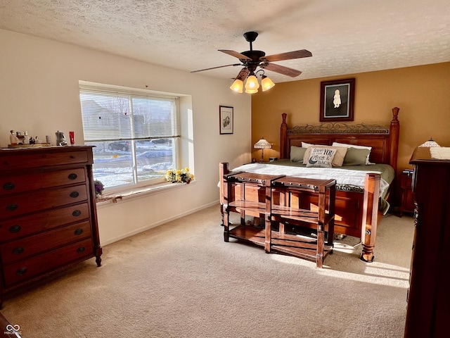 bedroom with ceiling fan, light colored carpet, and a textured ceiling