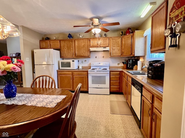 kitchen with pendant lighting, ceiling fan, sink, white appliances, and a textured ceiling