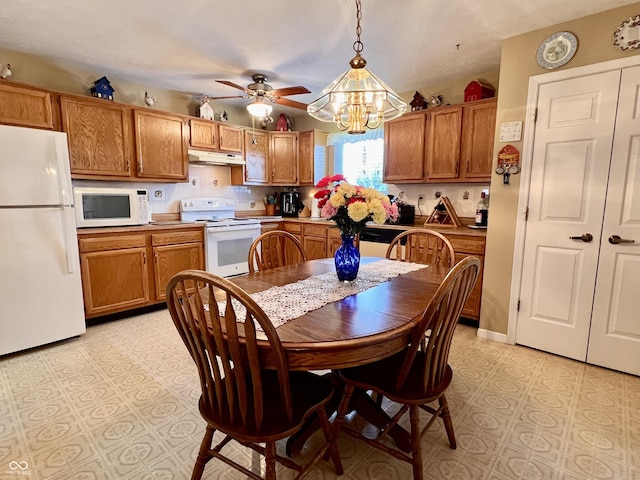 kitchen with ceiling fan with notable chandelier, white appliances, and hanging light fixtures