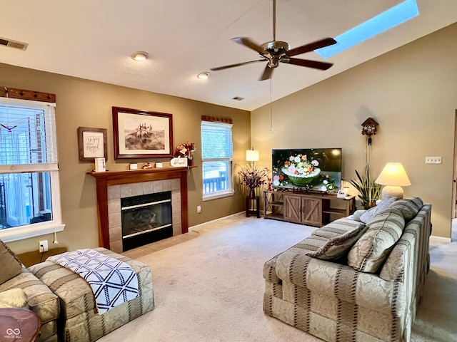 carpeted living room featuring vaulted ceiling, ceiling fan, and a tiled fireplace