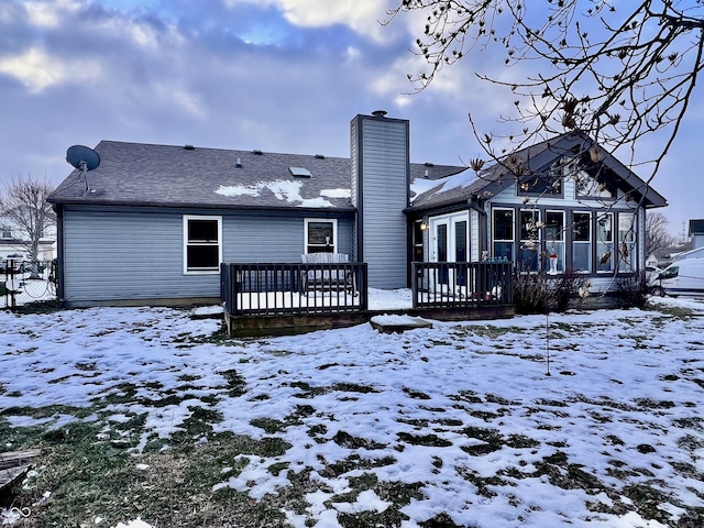 snow covered property with a sunroom and a deck