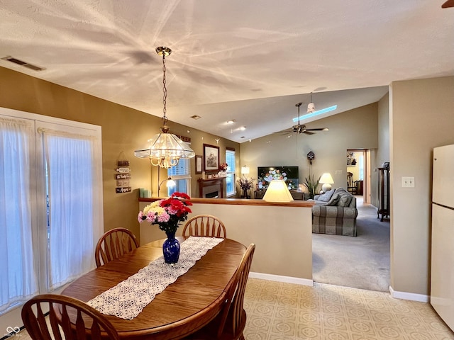 carpeted dining room with ceiling fan with notable chandelier and vaulted ceiling