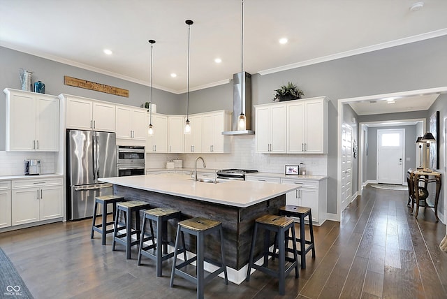 kitchen featuring sink, hanging light fixtures, a kitchen island with sink, stainless steel appliances, and wall chimney exhaust hood