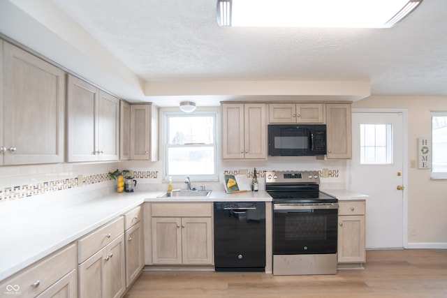 kitchen with black appliances, light brown cabinets, light hardwood / wood-style floors, sink, and plenty of natural light