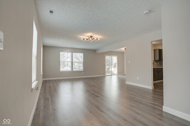 unfurnished living room featuring hardwood / wood-style flooring and a textured ceiling